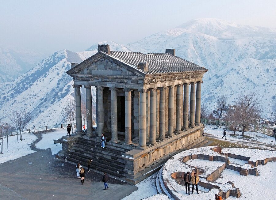 Aerial drone view of Garni Temple on a triangular cliff with the Gegham mountains behind