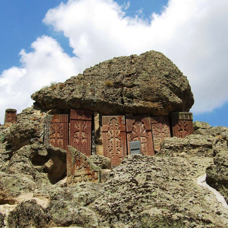 Khachkars carved directly into the cliff face at Geghard