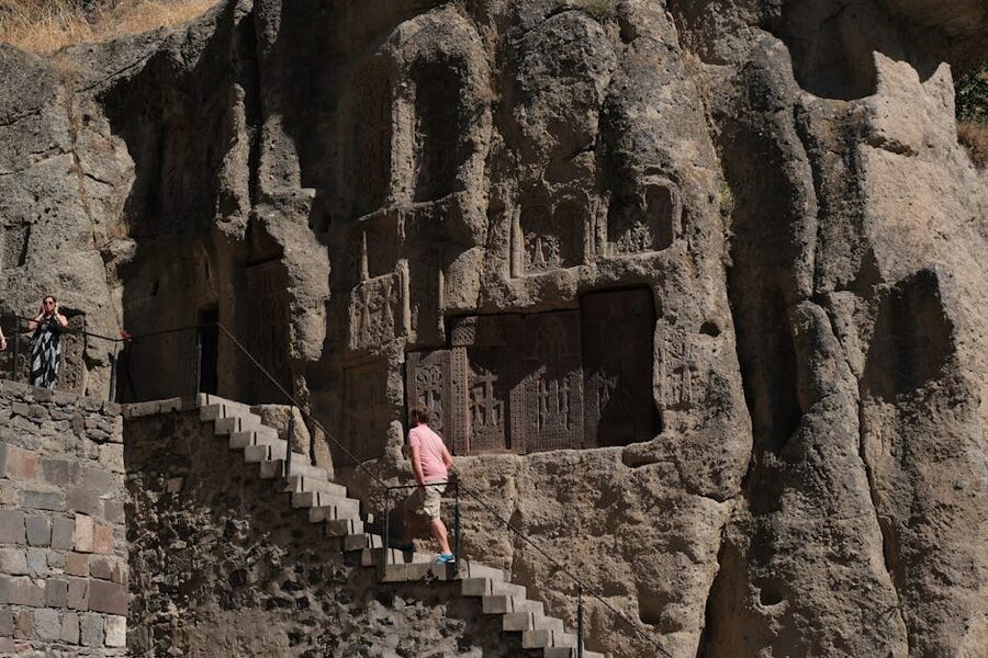 Visitors inside the rock-hewn carvings at Geghard Monastery