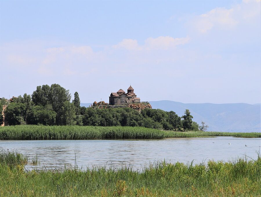 Hayravank Monastery viewed from the lakeshore with shallow water in the foreground