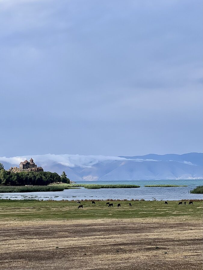 Hayravank Monastery perched on a rocky cliff edge above Lake Sevan, with khachkars in the foreground