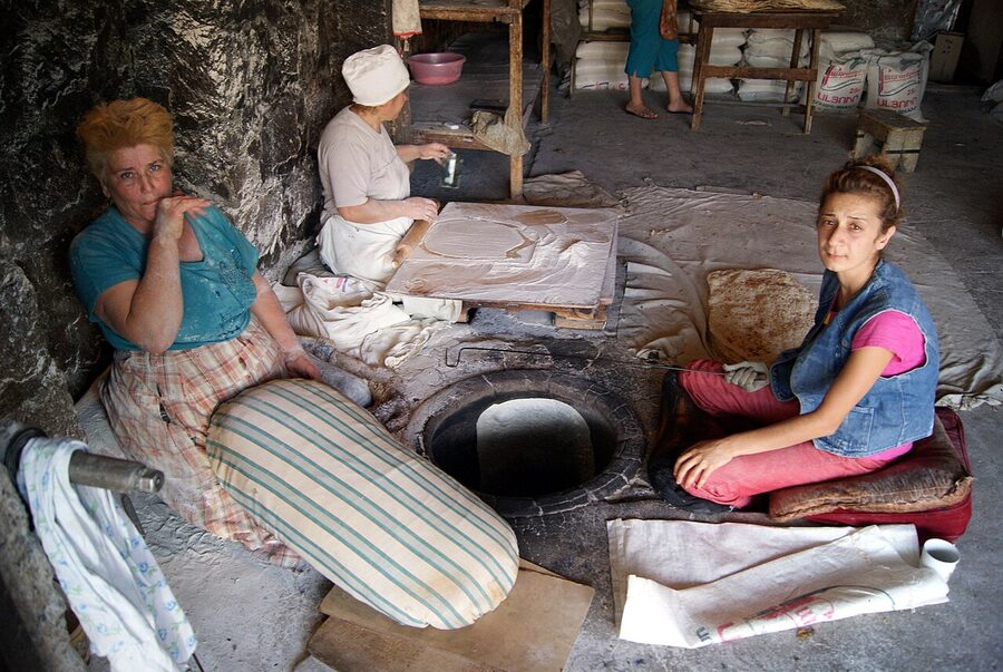 Two Armenian women baking lavash at a tonir oven